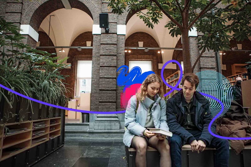 Two people sitting on bench looking at a book