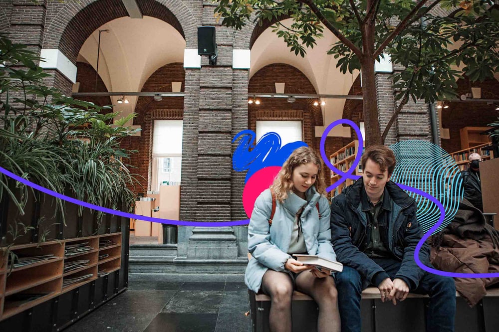 Two people sitting on bench looking at a book