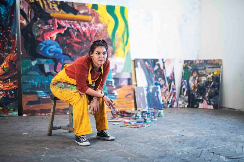 Person sitting on a chair holding a paint brush