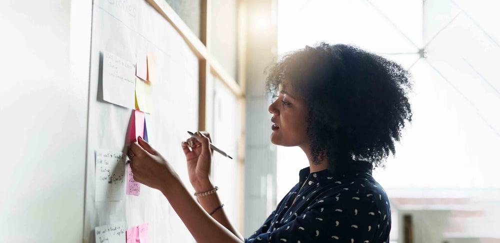 Person writing post it notes on a board