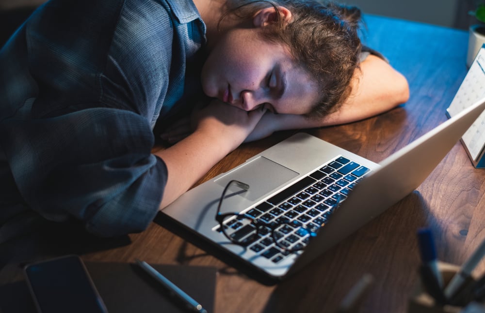 Tired person asleep with head on desk
