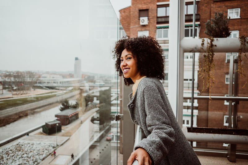 Person standing on a balcony outside and smiling