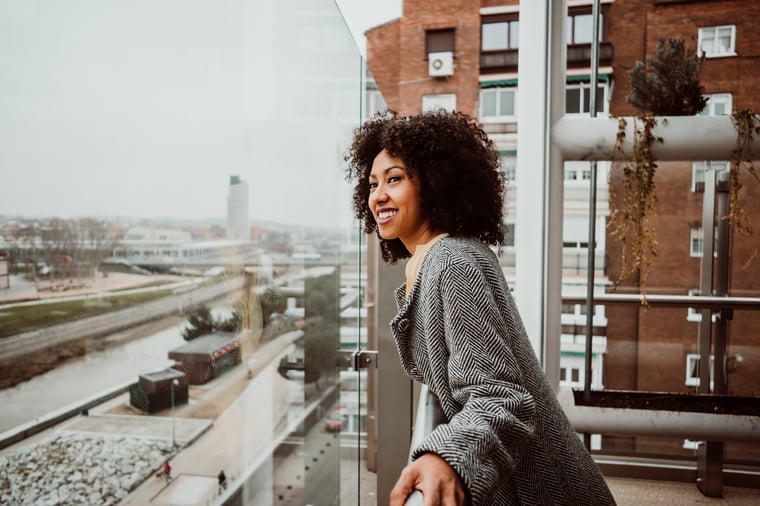 Person standing on a balcony outside and smiling
