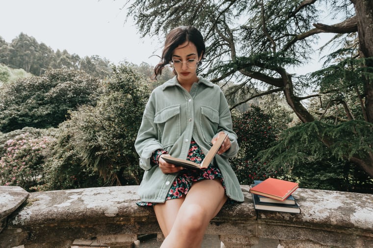 Student leaning on wall and reading a book