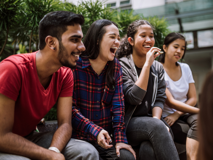group of students sitting next to each other laughing