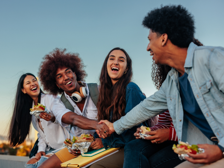 group of students eating and shaking hands outside