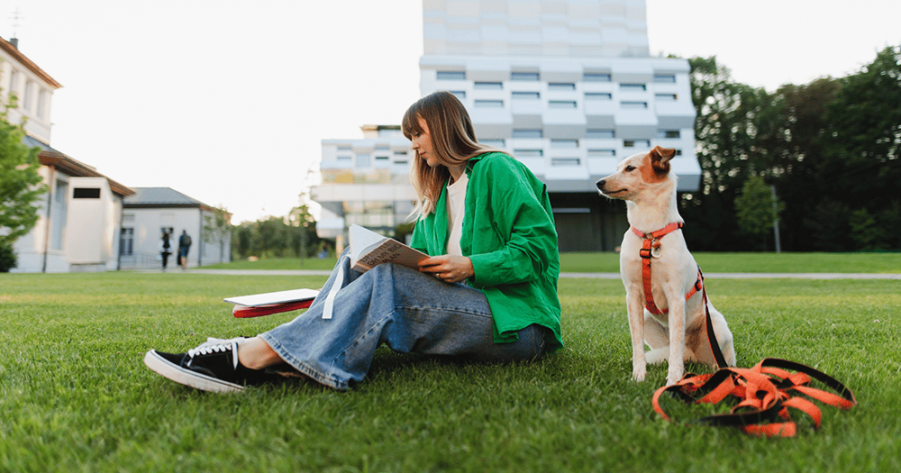 Person sitting on grass with a dog